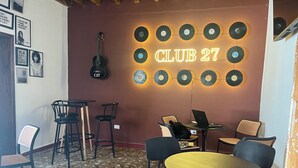 Une pièce dotée d’un présentoir mural pour platines vinyles, d’une guitare et de plusieurs options d’aménagement pour s’asseoir.