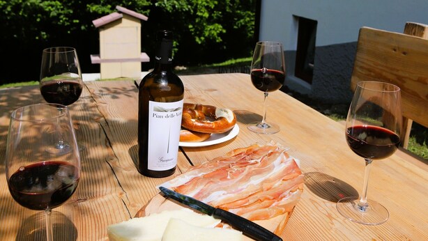 Ein Holztisch mit einer Weinflasche, Gläsern, Käse und einem Holzbrett.