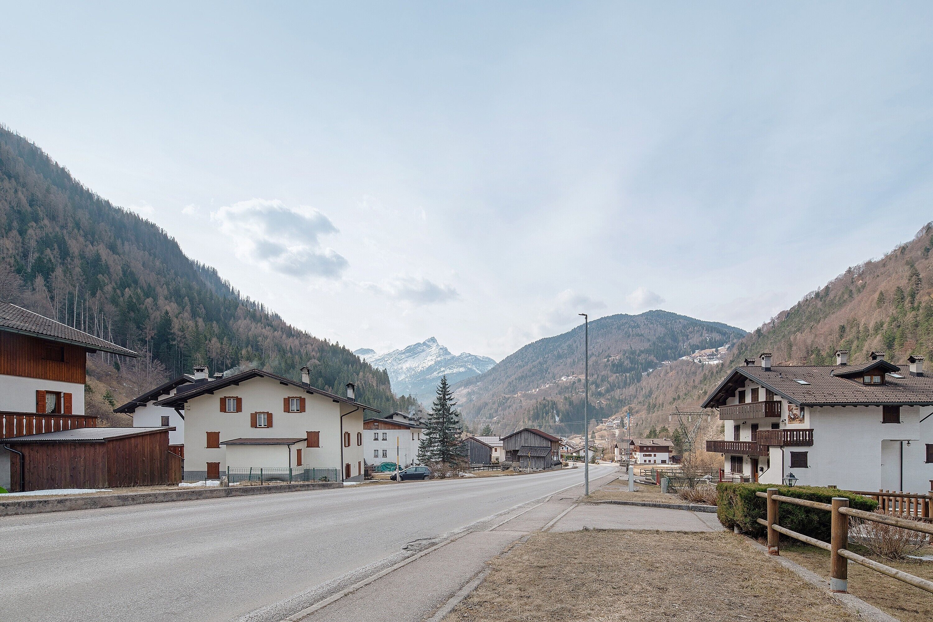 A mountain village with traditional wooden houses, a clear road, and a mountain backdrop.
