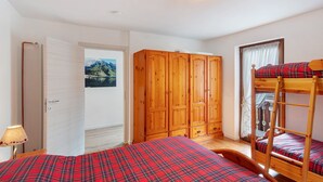 Ein Schlafzimmer mit Etagenbetten, einem Holzschrank und einer Tür zu einem anderen Raum.