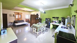A compact living space with a kitchenette, a dining area with a table and chairs, a sofa, and a small refrigerator.