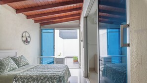 Un dormitorio con cama, mesita de noche y vistas al balcón.
