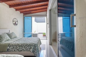 A bedroom with a bed, a bedside table, and a view of the balcony. - Family-friendly (Santo Domingo)