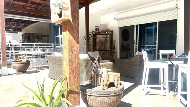 Un patio al aire libre con mobiliario de mimbre, una mesa de comedor y una planta en maceta.