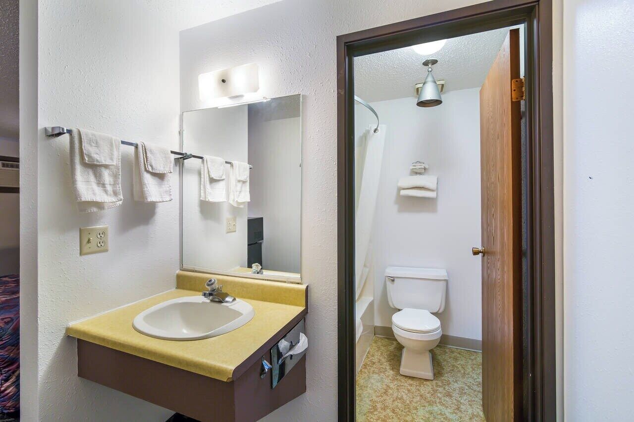 Une salle de bain avec un lavabo, un miroir et des toilettes.