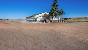 A single-story building with a flat roof, a covered porch, and a sign indicating it is a motel. - The Roosevelt Hotel & RV Park Gateway to Theodore Roosevelt National Park-Medora-on i-94 (Wibaux)