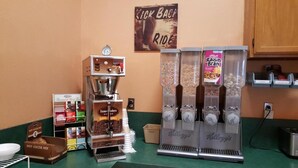 A coffee station with a coffee grinder, a Keurig coffee maker, and a Keurig coffee dispenser. There are also containers of coffee pods and a sign that says "Kick Back Ride". - The Roosevelt Hotel & RV Park Gateway to Theodore Roosevelt National Park-Medora-on i-94 (Wibaux)