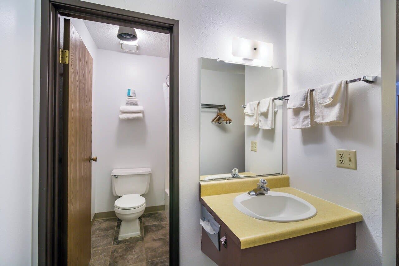 Ein Badezimmer mit Toilette, Waschbecken, Spiegel und Handtuchhalter.