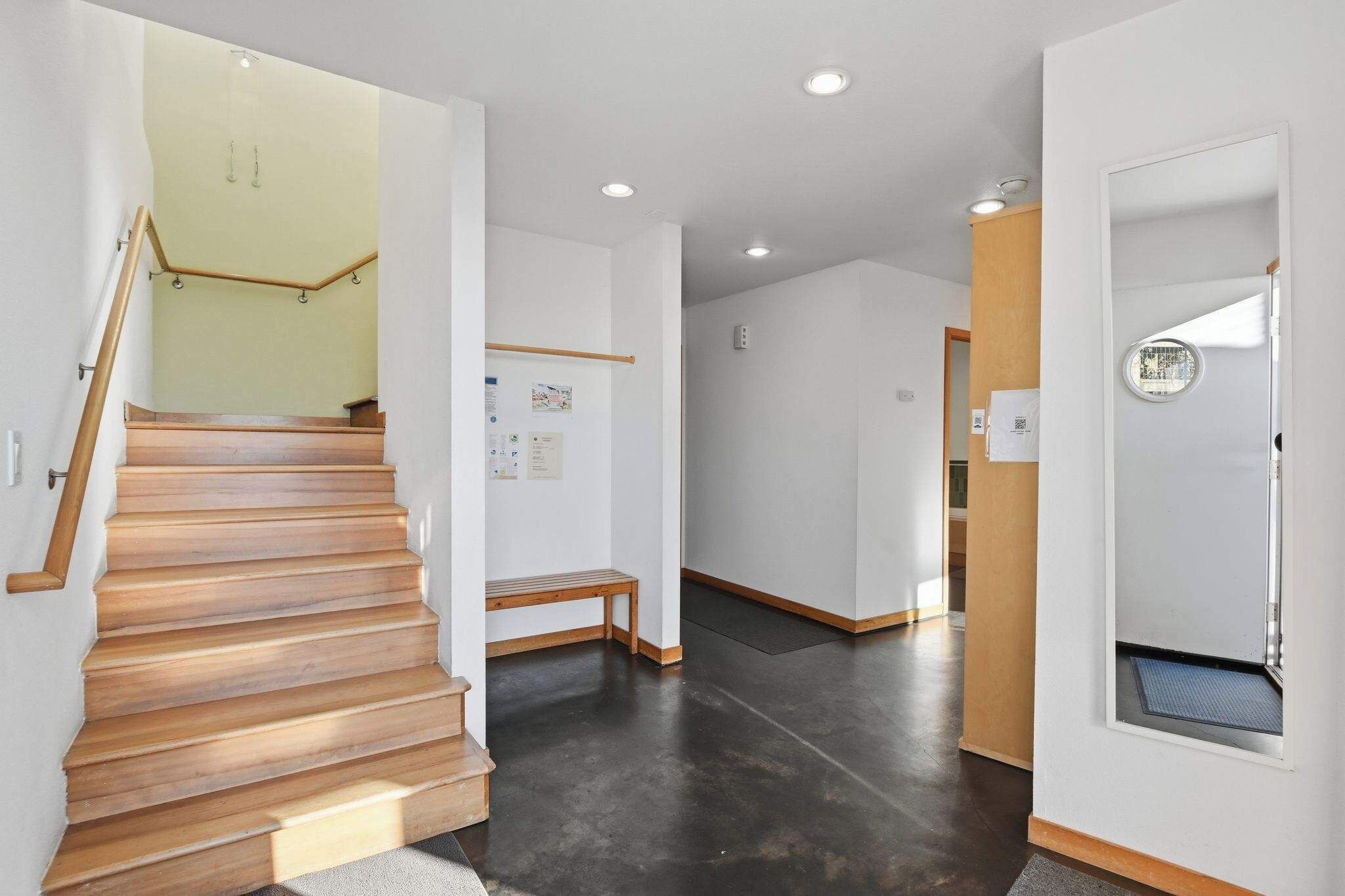 Un interior moderno con una escalera de madera, un banco y una ventana pequeña con vistas.
