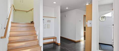 Un interior moderno con una escalera de madera, un banco y una ventana pequeña con vistas.