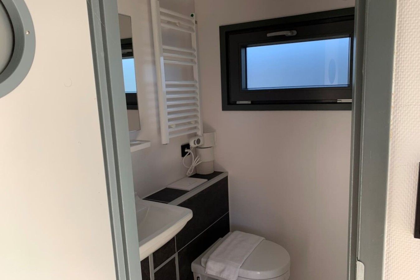 Et lille badeværelse med toilet, vask og fast installeret varme.