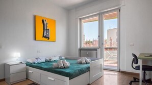 A modern bedroom with a bed, bedside tables, a desk, and a window with a view of the outside.