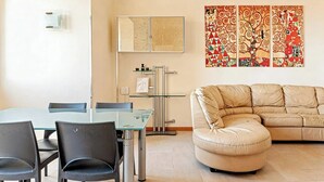A modern living room with a glass dining table, black chairs, a beige sofa, and a colorful abstract painting on the wall. - Roby's Panoramic House: A Corner of Paradise in Livorno (Livorno)