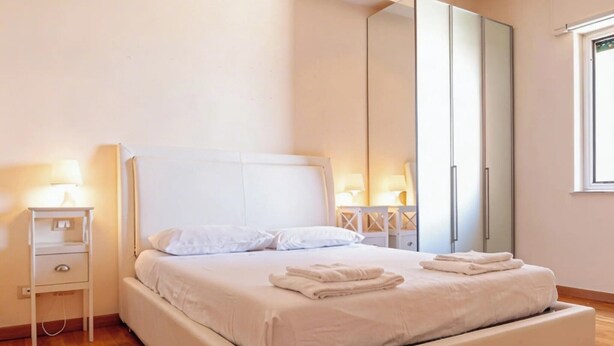 A modern bedroom with a large bed, bedside tables with lamps, and a wardrobe. - Roby's Panoramic House: A Corner of Paradise in Livorno (Livorno)