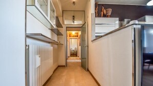 A narrow hallway with a radiator on the left, a refrigerator on the right, and a door leading to another room. - Roby's Panoramic House: A Corner of Paradise in Livorno (Livorno)