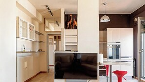 A modern living room with a flat-screen TV, a black leather sofa, and a red bar stool. - Roby's Panoramic House: A Corner of Paradise in Livorno (Livorno)