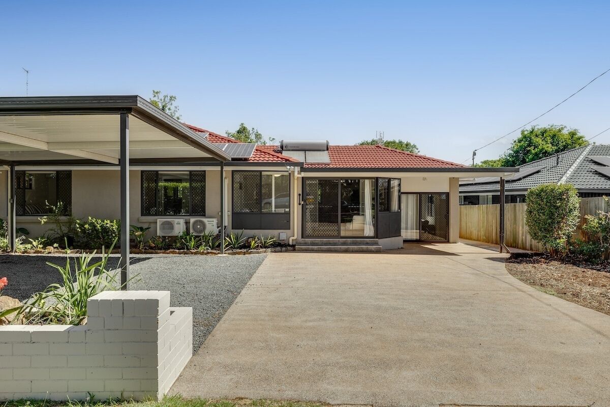 Ein modernes Haus mit überdachter Terrasse, Solaranlage und rotem Ziegeldach.