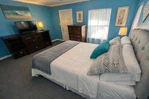 A bedroom with a bed, a dresser, a television, and artwork on the walls. - Clean, Quiet Private Suite w/ Hot Tub • Near Fort Benning/Midtown (Columbus)