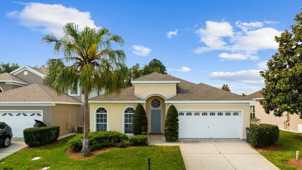 A single-story house with a garage, a front yard with a palm tree, and a mailbox. - South Facing Pool 4 Bedroom 3 Bath Villa - Just Minutes from Disney World! (Kissimmee)