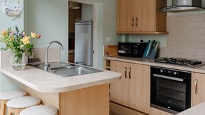 Een moderne keuken met een centraal eiland, roestvrijstalen apparatuur en houten kastjes.