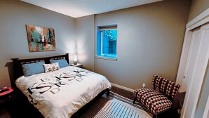 A bedroom with a bed, a nightstand, a window, and a chair. - Spacious private whole guest house in NE Portland! (Portland)