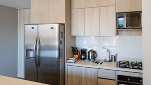 A modern kitchen with stainless steel appliances, wooden cabinets, and a microwave.