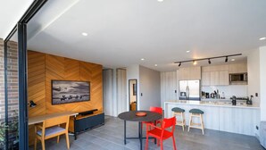 A modern kitchen with a central island, built-in appliances, and a herringbone wood wall.