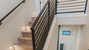 Un escalier avec des marches en bois et des rampes en métal noir, menant à l’étage supérieur.