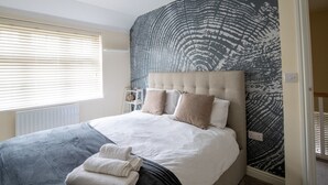 Une chambre à coucher avec un grand lit, une tête de lit et un mur décoré d’un motif.