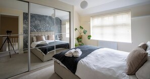 Ein Schlafzimmer mit einem Bett, einem Spiegel, einer Pflanze und einer Kamera auf einem Stativ.