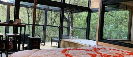 A bedroom with a large bed, a wooden desk, and a fireplace.