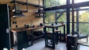Uma cozinha moderna com uma ilha central, mobiliário preto e amplas janelas com vista para o exterior.
