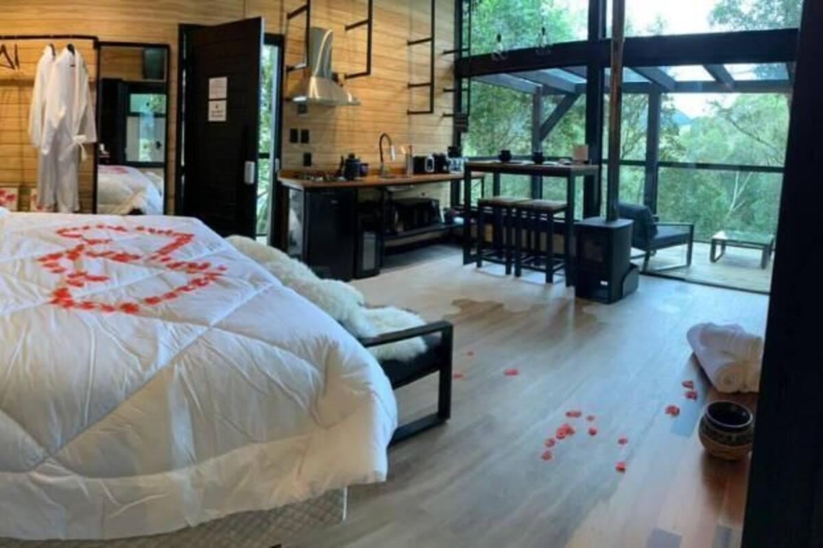 A cozy bedroom with a large bed, wooden walls, a desk, and a view of the outdoors.