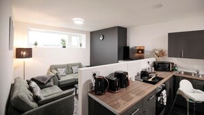 Une cuisine moderne avec un plan de travail en bois, une machine à café, un grille-pain et un four à micro-ondes. On y trouve également un canapé et un coin repas avec une chaise.