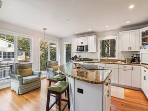 A modern kitchen with a large island, white cabinetry, and a view of the outdoors. - Waterfront 4BR House w/ Private Dock | Nr Beaches! (Bethany Beach)