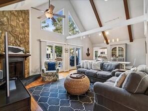 A spacious living area with a fireplace, a large sofa set, a dining table, and a ceiling fan. - Waterfront 4BR House w/ Private Dock | Nr Beaches! (Bethany Beach)