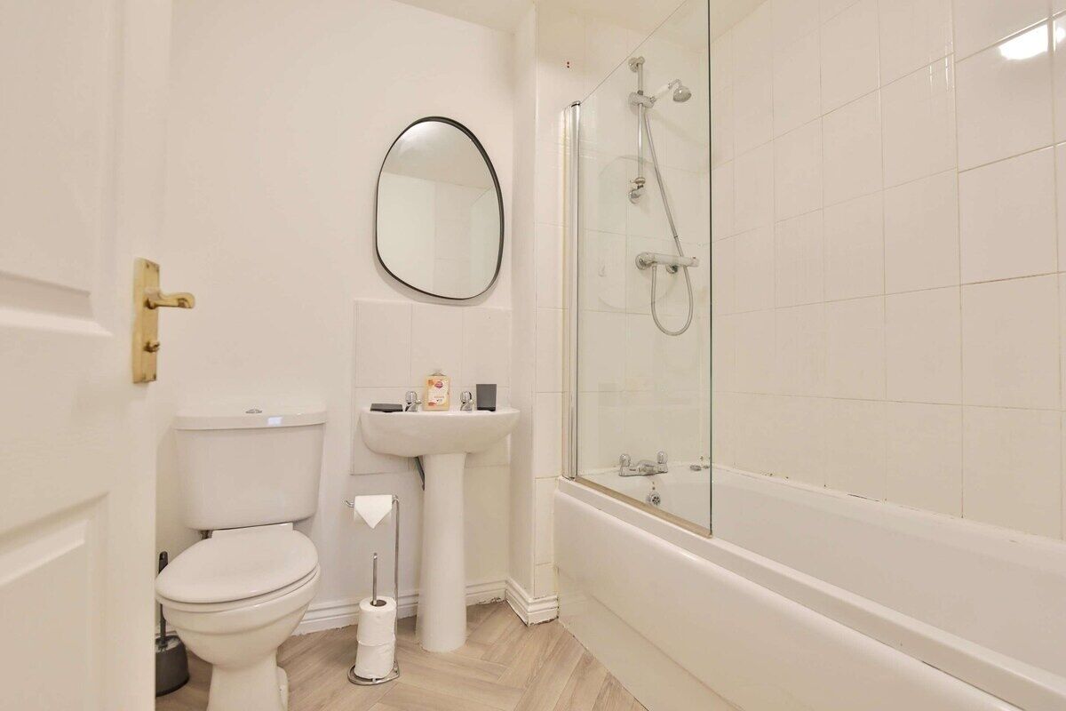 Een badkamer met toilet, wastafel, spiegel en douche met glazen wanden.