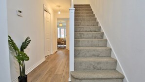 A carpeted staircase in a hallway with wooden flooring and a potted plant. - Littlebrooke House | Bolton | Free Parking (Bolton)