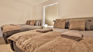 A bedroom with two beds, each with a beige blanket and pillows. - Littlebrooke House | Bolton | Free Parking (Bolton)