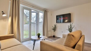 A modern living room with a sofa, a coffee table, and a TV mounted on the wall. - Littlebrooke House | Bolton | Free Parking (Bolton)