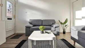 A modern living room with a grey sofa, a white coffee table, and a potted plant. - Athol House, 2BR near Trafford Park, Free Parking (Salford)