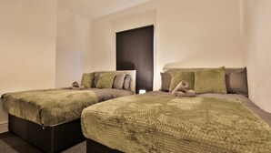 Two single beds with green and brown bedding, a dark door, and a plain white wall. - Athol House, 2BR near Trafford Park, Free Parking (Salford)