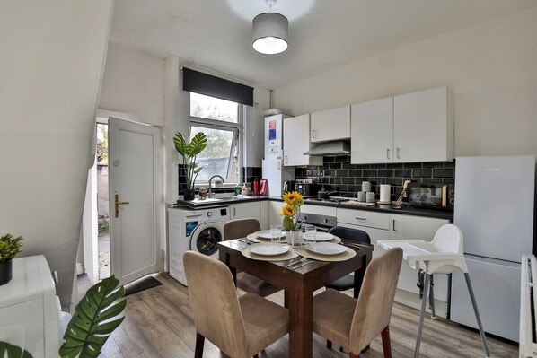 A modern kitchen with white cabinets, a built-in oven, and a dining area with a table set for four.