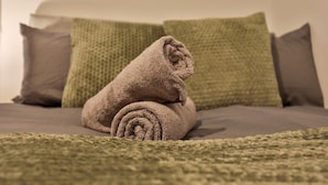 A neatly made bed with a rolled-up towel and two pillows. - Athol House, 2BR near Trafford Park, Free Parking (Salford)
