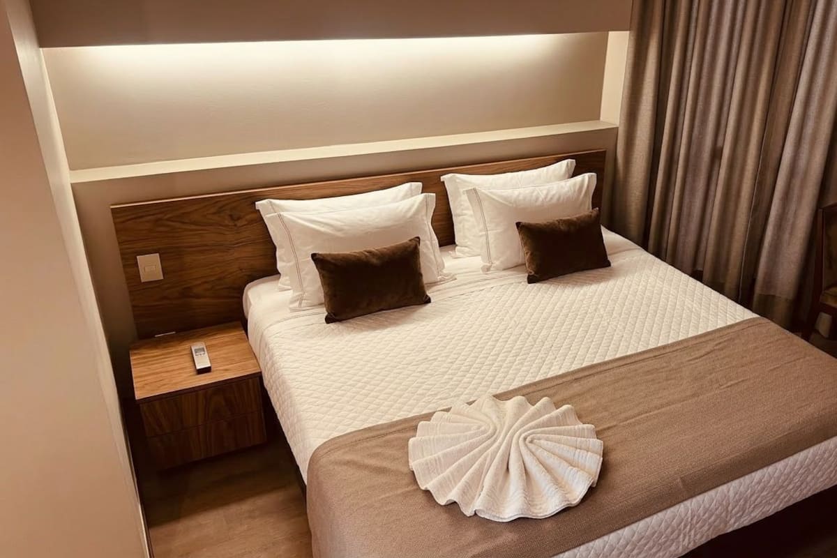 Ein Hotelzimmer mit einem Bett, einem Nachttisch, einer Fernbedienung und einem Vorhang.