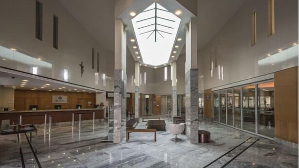 Un hall d’entrée spacieux avec un plafond haut, un sol en marbre, un comptoir de réception et un espace détente.