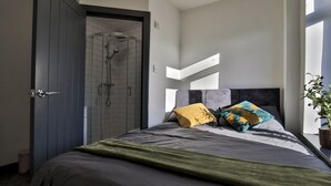 Ein modernes Schlafzimmer mit einem großen Bett, einer Dusche und Blick ins Freie.