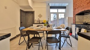 A modern kitchen with a dining area, featuring a brick wall, a large window, and a built-in oven. - Chesterfield House, 7BR, Blackpool (Blackpool)