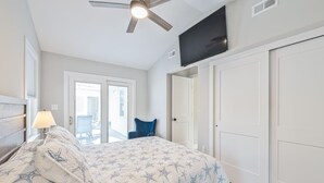 Ein Schlafzimmer mit Bett, Deckenventilator, Fernseher und einer Tür.