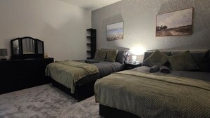 Ein Schlafzimmer mit zwei Einzelbetten, einem Schminktisch, einem Spiegel und Wandbildern.